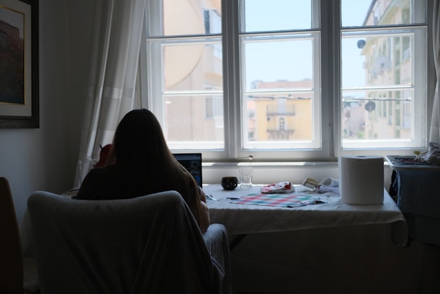 adult student studying at home laptop window