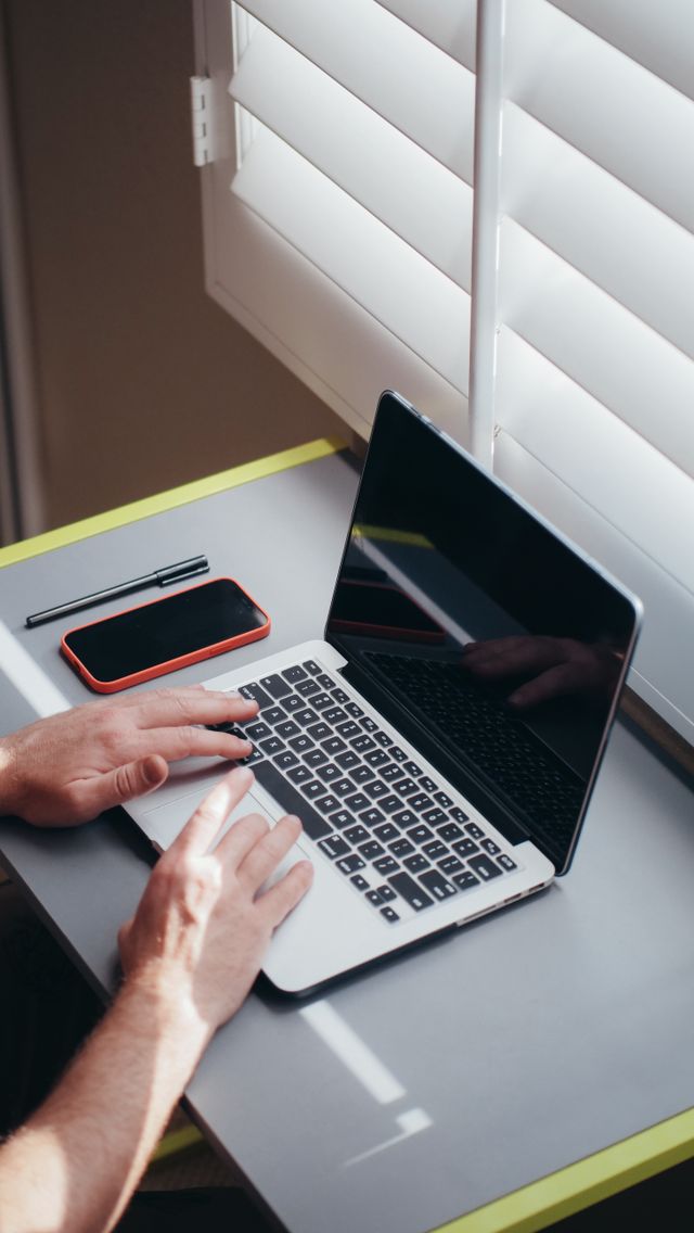 person using laptop with smartphone desk